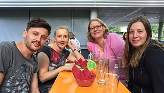 Mitarbeiter sitzen beim BKK Sommerfest zusammen am Tisch im grünen Innenhof der Verbandszentrale